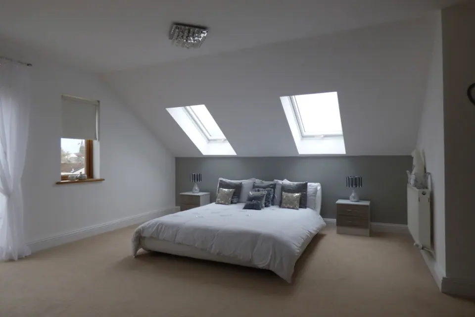 An attic bedroom under a sloping ceiling with two roof windows