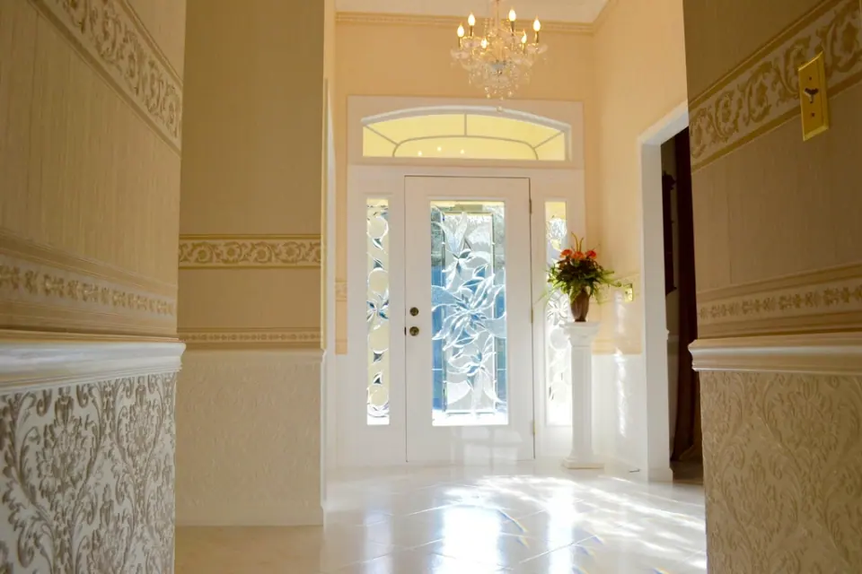 A cream-coloured hallway with an arched opening and a glazed front door